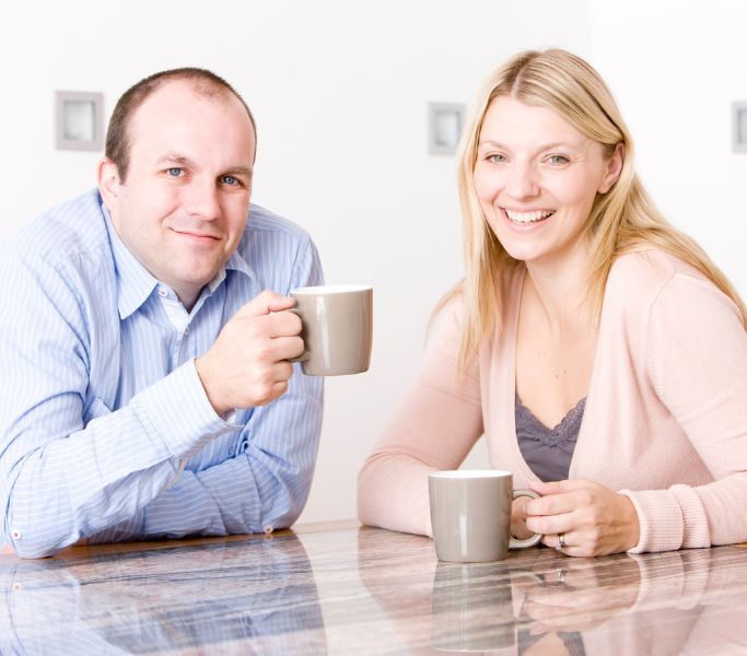 a man and woman sitting at a table drinking coffee