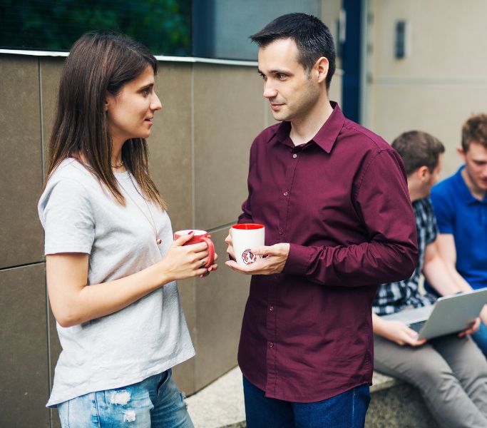 A woman and guy on coffee break outside.